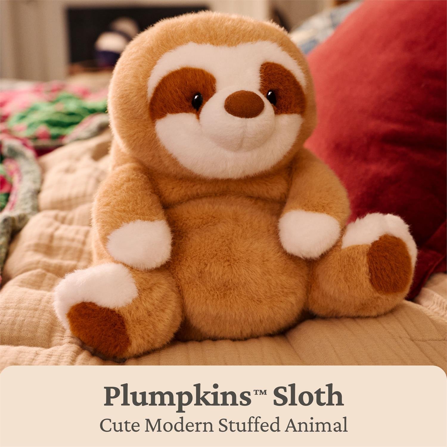 A plush sloth toy sitting on a bed with a beige quilt, a red pillow, and a blurred bedroom background. Text at the bottom reads 'Plumpkins Sloth' and 'Cute Modern Stuffed Animal'.