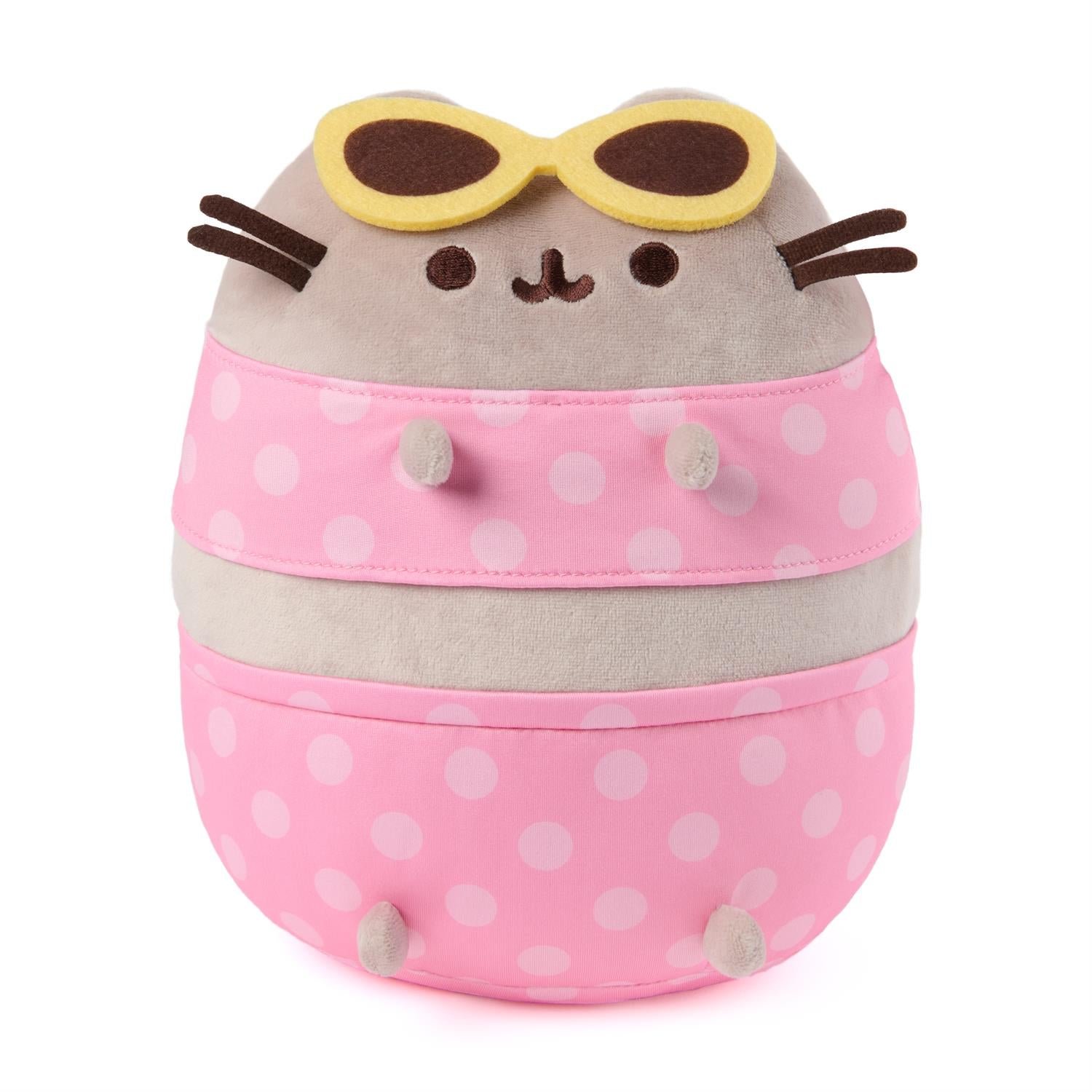 Plush toy resembling a cat with polka dot pink bag and sunglasses on a white background